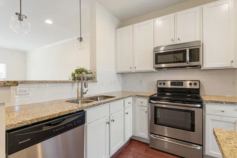 a kitchen with granite countertop a sink stove and microwave