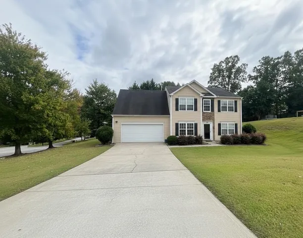 a front view of a house with a garden and trees