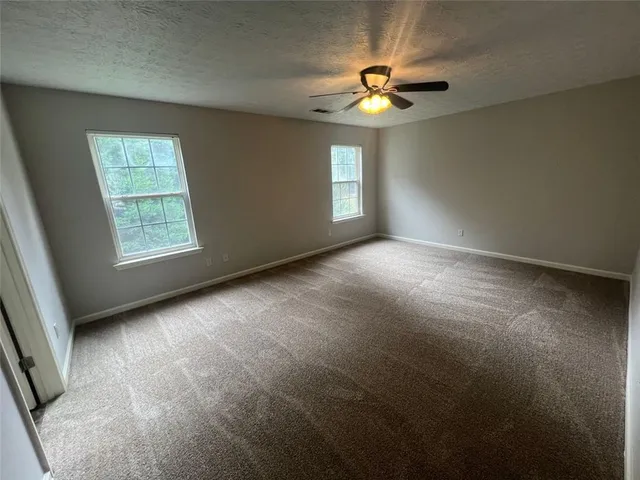 an empty room with windows and chandelier fan