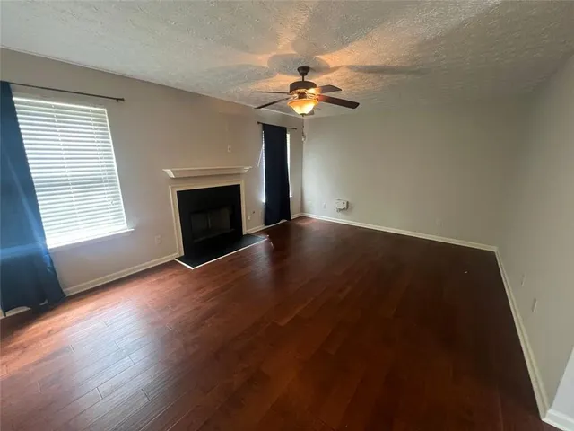 an empty room with wooden floor chandelier fan and windows