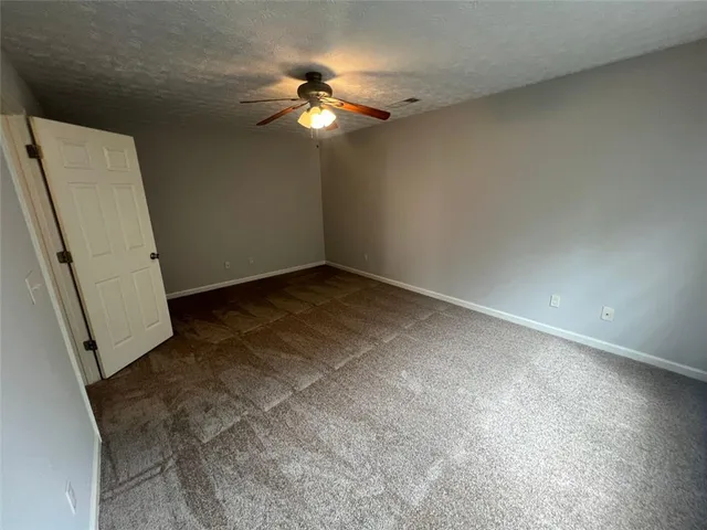 an empty room with a chandelier fan and a large window