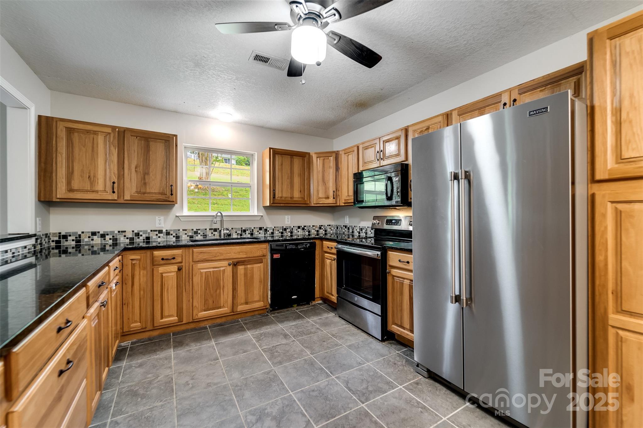 1061 Calvary Church Road Sylva, NC 28779 - Photo 14 of 46 a large kitchen with stainless steel appliances granite countertop a refrigerator a sink dishwasher a stove with wooden cabinets and floor