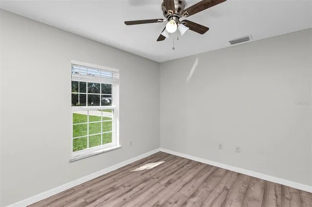 an empty room with windows and fan