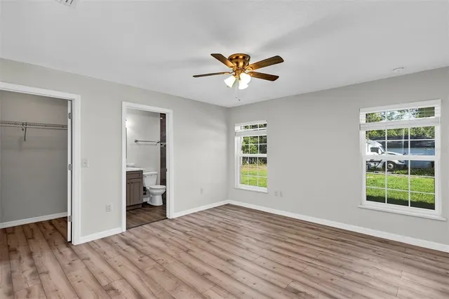 a view of empty room with wooden floor and fan