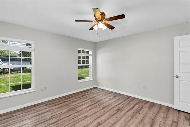 a view of an empty room with a window and wooden floor