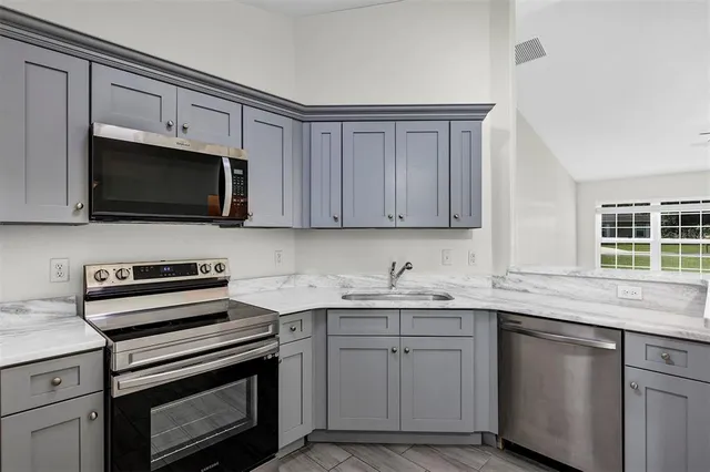 a kitchen with stainless steel appliances granite countertop a sink dishwasher a stove and a microwave oven with cabinets