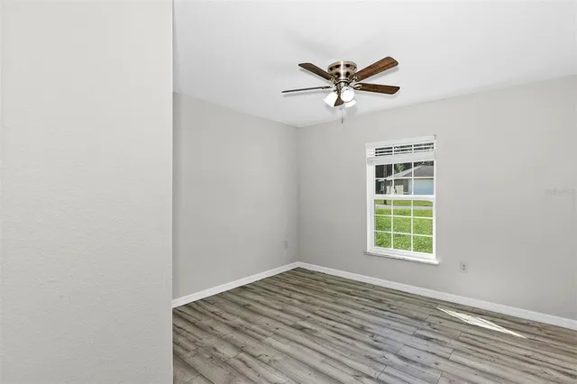 an empty room with windows and fan