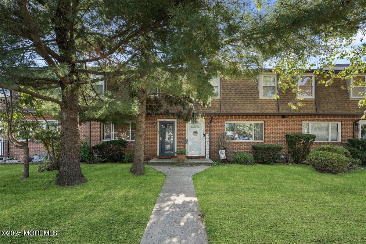 a front view of a house with garden and trees