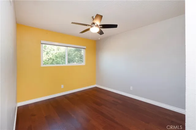 an empty room with a hardwood and ceiling fan