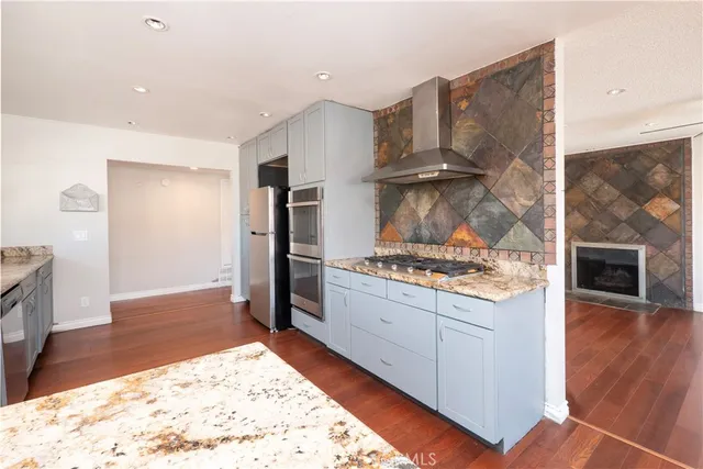 a kitchen with stainless steel appliances granite countertop a stove a refrigerator and a wooden cabinets