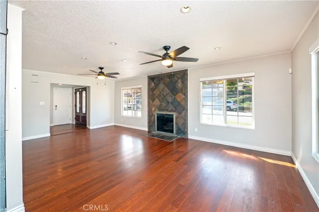an empty room with wooden floor a fireplace and windows