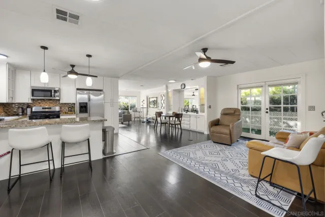 a living room with furniture kitchen view and a wooden floor