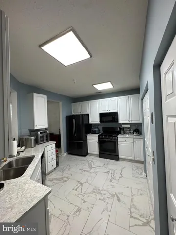 a kitchen with stainless steel appliances a stove a sink a microwave a refrigerator and cabinets