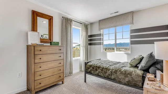 a bedroom with a bed a window and potted plant on the table