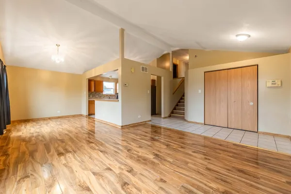 a view of an empty room and kitchen with a sink
