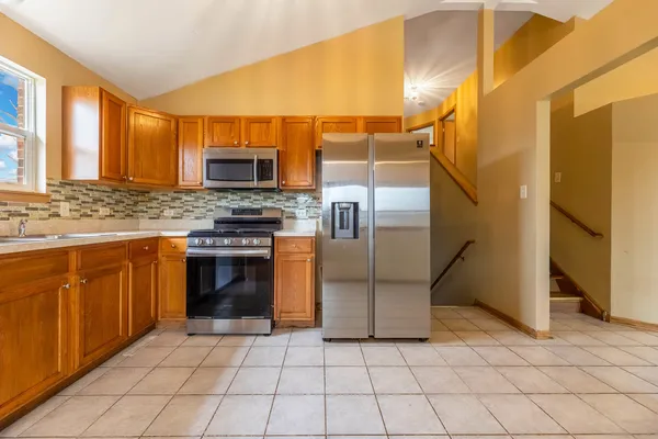 a kitchen with stainless steel appliances granite countertop a refrigerator a stove a sink and a microwave