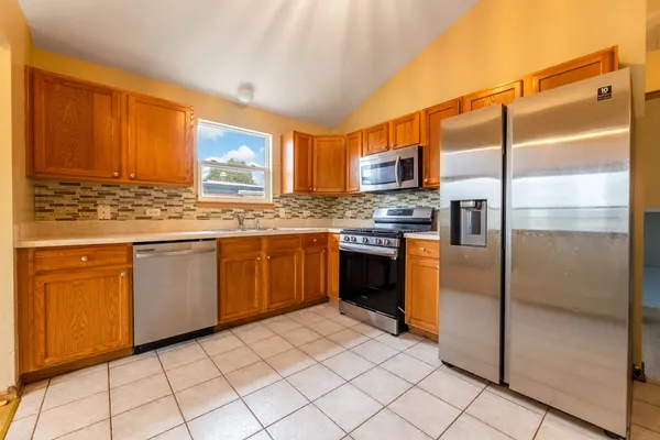 a kitchen with stainless steel appliances granite countertop a stove a sink and a refrigerator