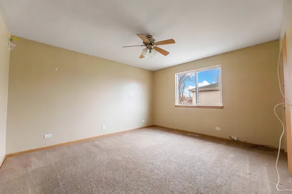an empty room with windows and ceiling fan
