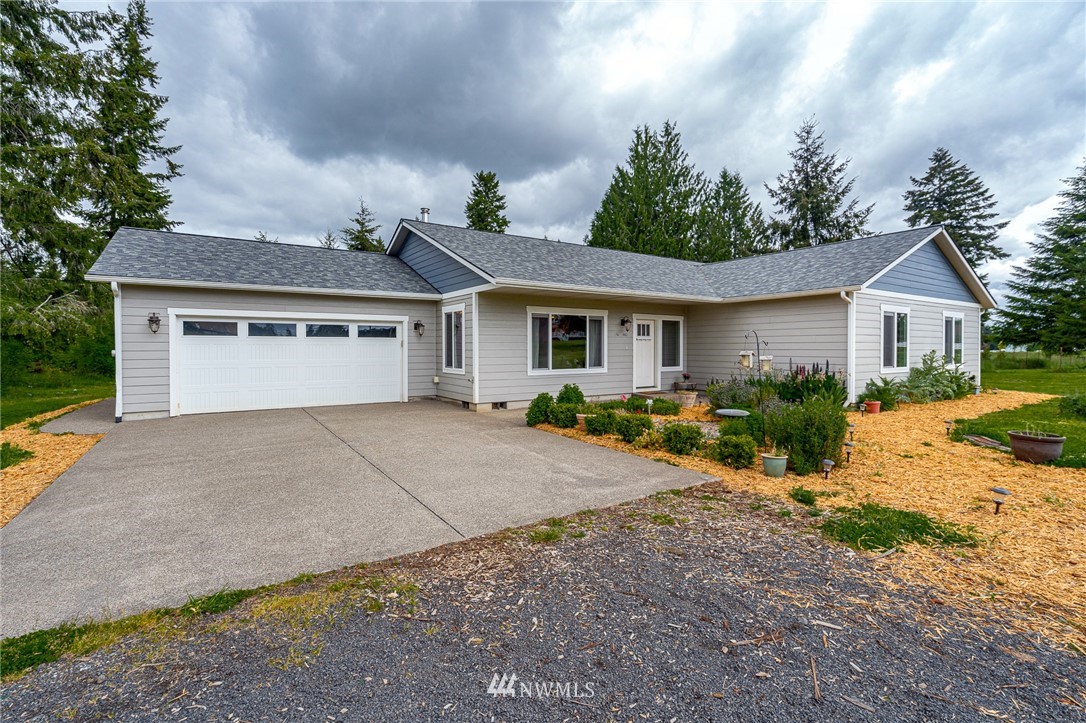 665 Rhoades Road Winlock, WA 98596 - Photo 1 of 39 a view of a house with a yard and table and chairs under an umbrella