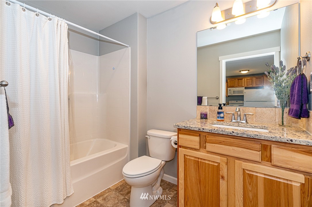 665 Rhoades Road Winlock, WA 98596 - Photo 32 of 39 a bathroom with a granite countertop sink toilet a mirror a bathtub and shower