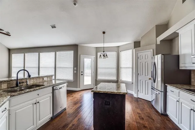 a large kitchen with a large window a sink stainless steel appliances and cabinets