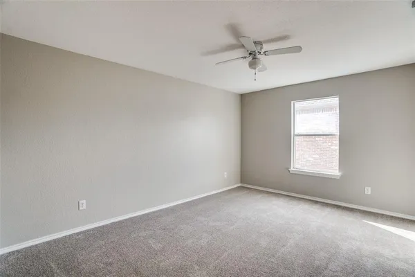 an empty room with a window and a ceiling fan