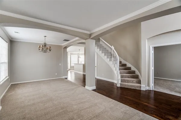 a view of an empty room with wooden floor and stairs