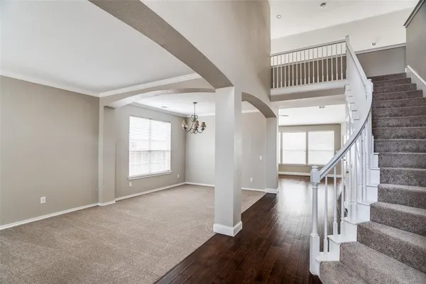 a view of an empty room with wooden floor and stairs