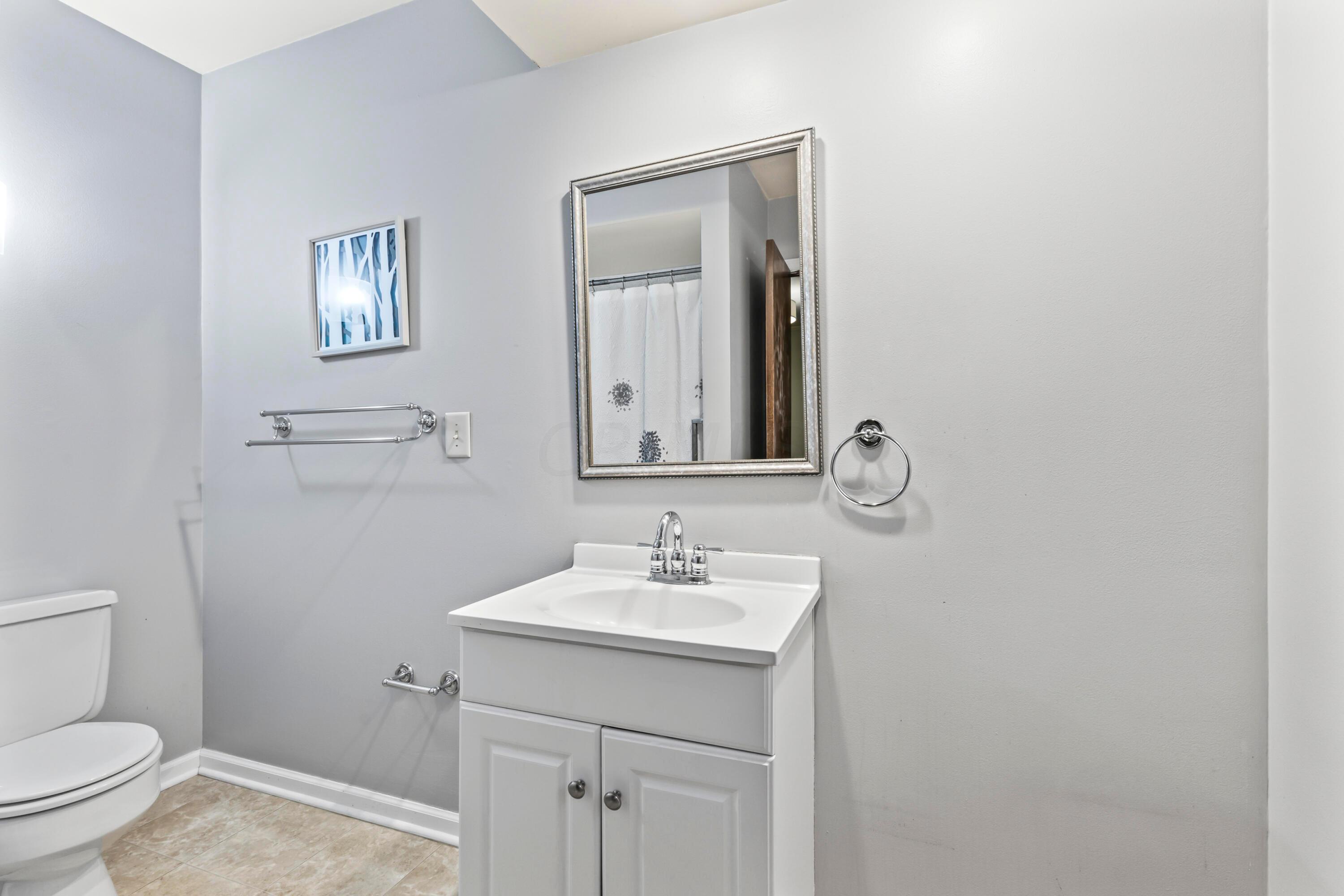 7020 Rieber Street Columbus, OH 43085 - Photo 26 of 40 • New neutral vinyl flooring ~ 2006 • Grey painted walls • Enclosed vanity with single bowl, cultured marble sinktop • Ceiling exhaust • Tub/shower combination with ceramic tile surround • Wall mounted light • 2” blinds
