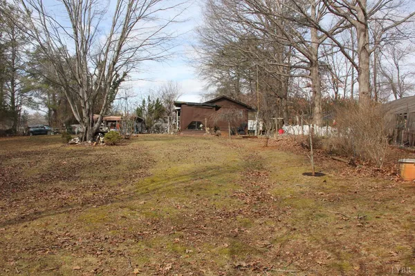a backyard of a house with large trees and outdoor seating