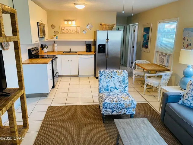 a living room with stainless steel appliances kitchen island granite countertop furniture and a rug