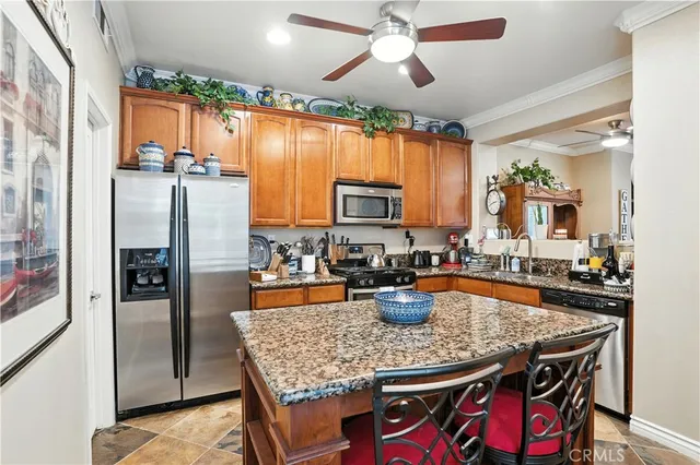 a kitchen with stainless steel appliances granite countertop a dining table chairs refrigerator and sink
