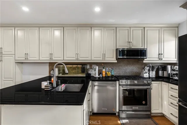a kitchen with granite countertop a stove a sink and a white cabinets