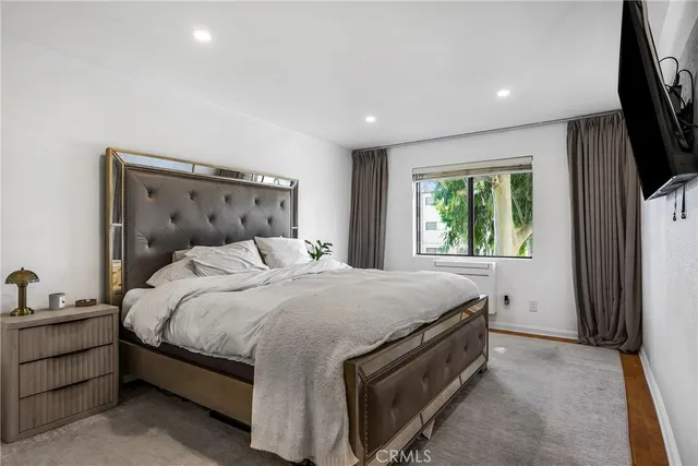 a bedroom with a bed and a flat tv screen on dresser