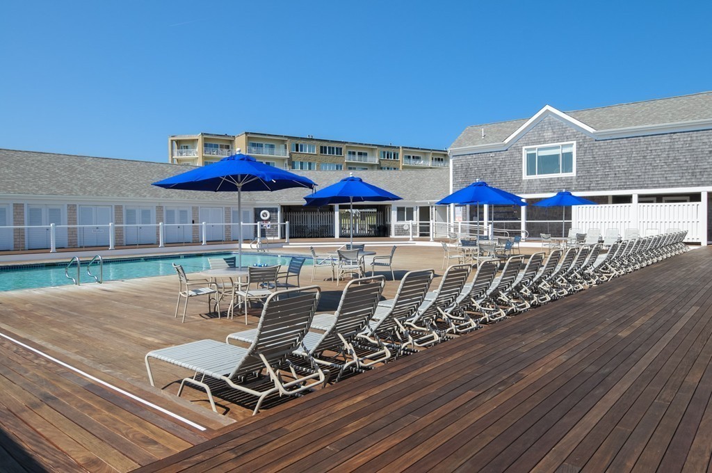 1 Belmont Road, Unit 223 West Harwich, MA 02671 - Photo 22 of 23 a view of a patio with table and chairs under an umbrella with wooden floor