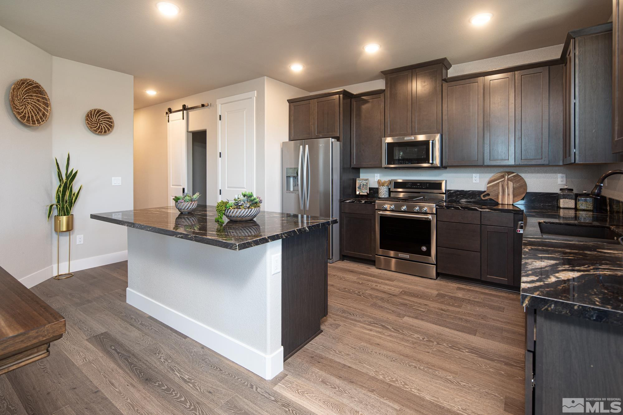 7719 Enclave Key Road Reno, NV 89506 - Photo 19 of 26 a kitchen with stainless steel appliances granite countertop a refrigerator a stove a sink and a microwave