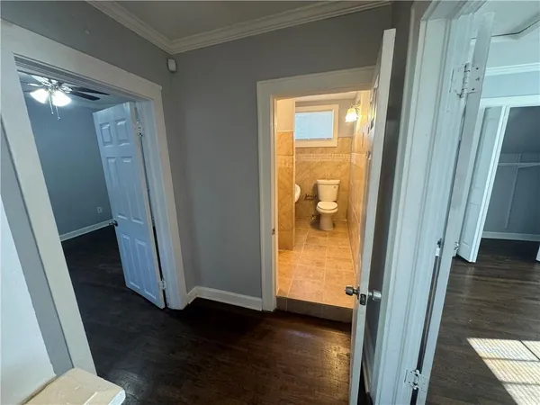 a view of a hallway with wooden floor and a bathroom