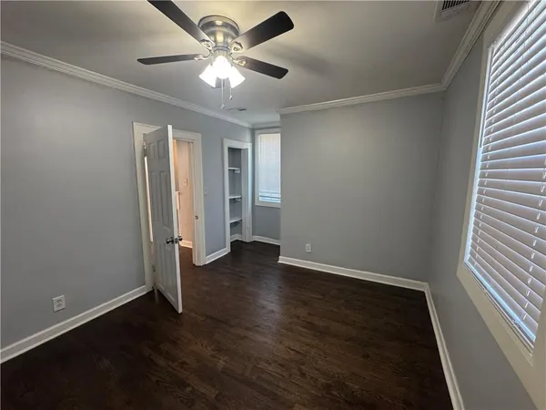 an empty room with wooden floor and ceiling fan