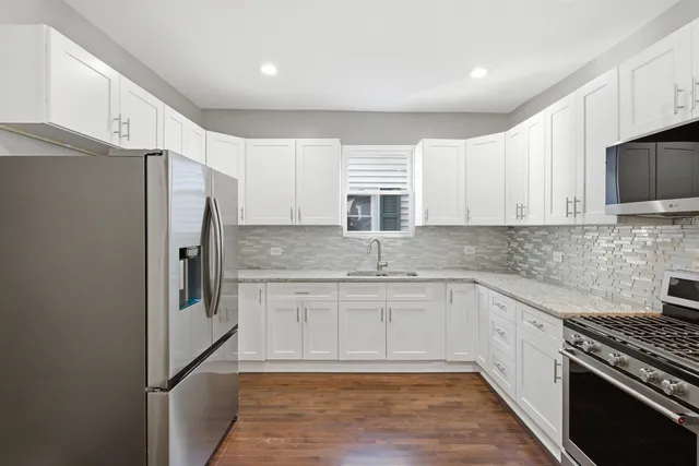 a kitchen with stainless steel appliances granite countertop a refrigerator and a stove top oven