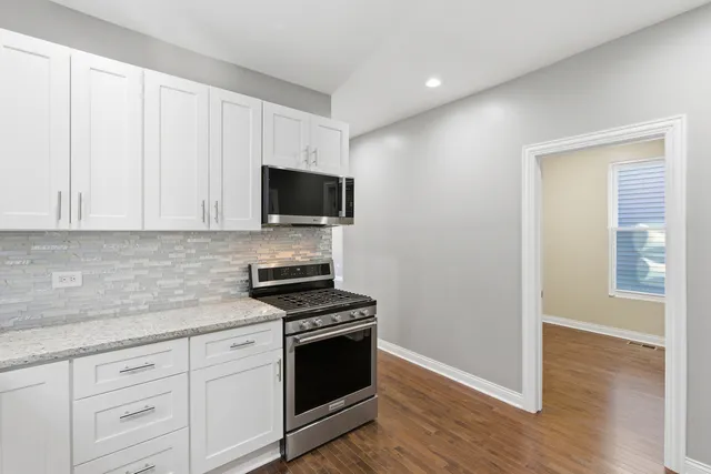 a kitchen with white cabinets stainless steel appliances and wooden floor