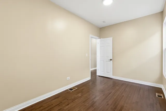 an empty room with wooden floor and white wall