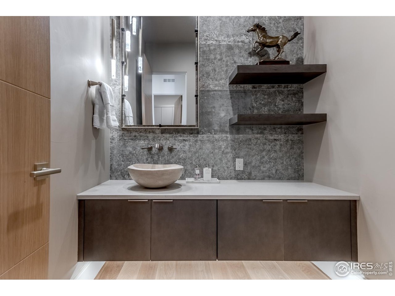 7572 Raphael Lane Littleton, CO 80125 - Photo 25 of 50 The main-level powder bath makes a bold impression: a floating vanity beneath decorative lighting, an artisanal stone sink, and a textured tile accent wall. Every surface feels curated for visual impact and tactile delight.