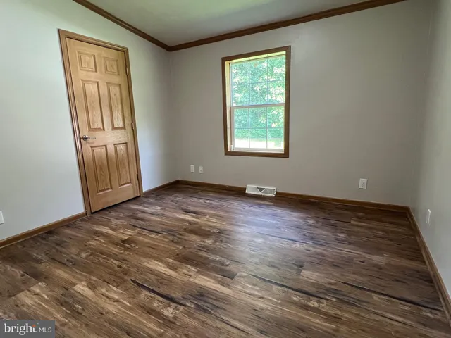 an empty room with wooden floor cabinet and windows