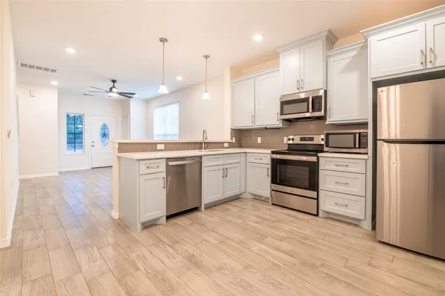 a kitchen with white cabinets and stainless steel appliances