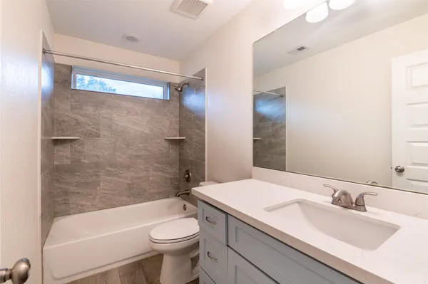 a bathroom with a granite countertop sink toilet mirror and bathtub