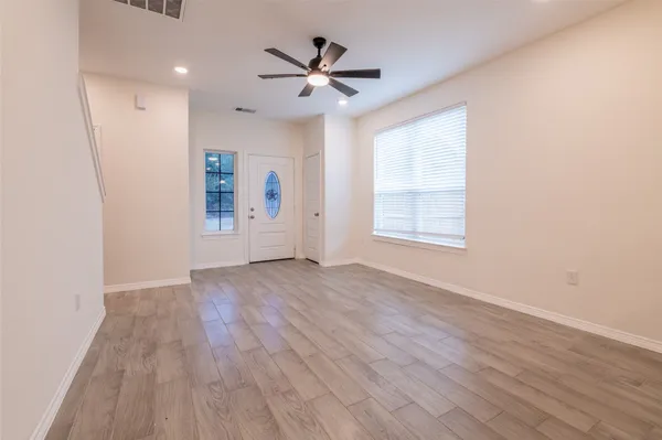 an empty room with wooden floor and windows