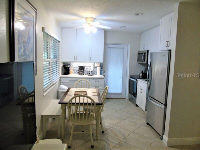 6020 Midnight Pass Road, Unit 3 Sarasota, FL 34242 - Photo 8 of 13 a kitchen with stainless steel appliances a refrigerator a stove a sink dishwasher and a refrigerator with wooden floor