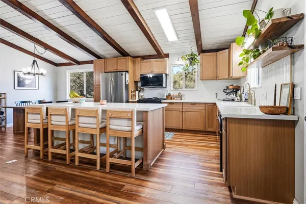 a kitchen with stainless steel appliances granite countertop a refrigerator a sink dishwasher a stove and white countertops with wooden floor