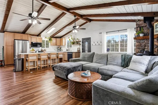 a kitchen with stainless steel appliances granite countertop a refrigerator a sink dishwasher a stove and a dining table with wooden floor