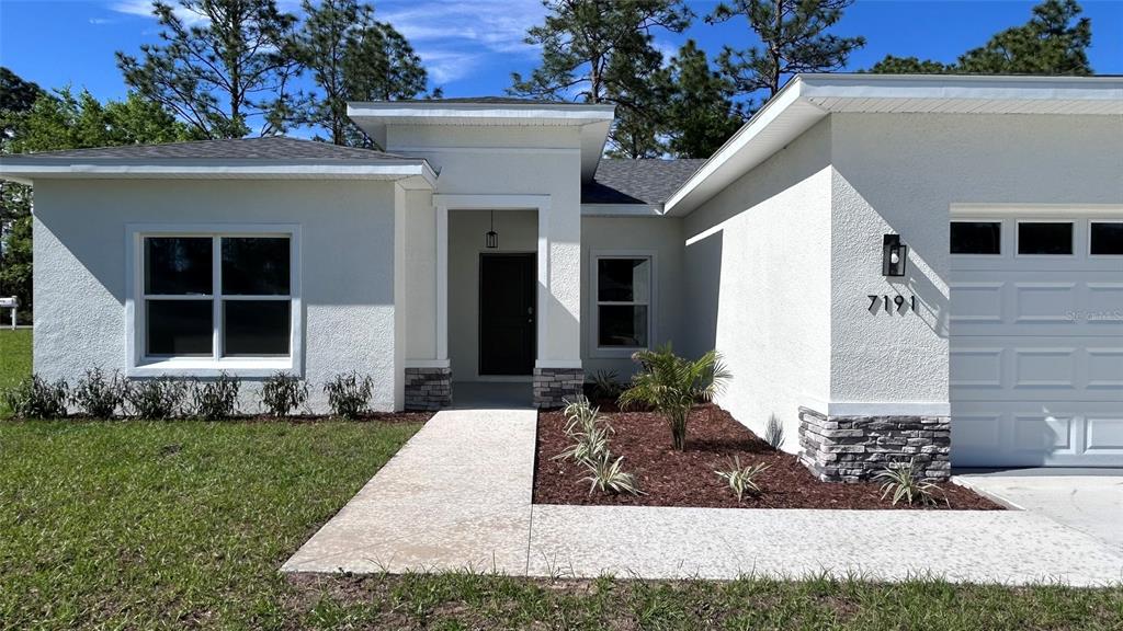 7191 Southwest 133rd Lane Ocala, FL 34473 - Photo 3 of 20 a front view of a house with a garden